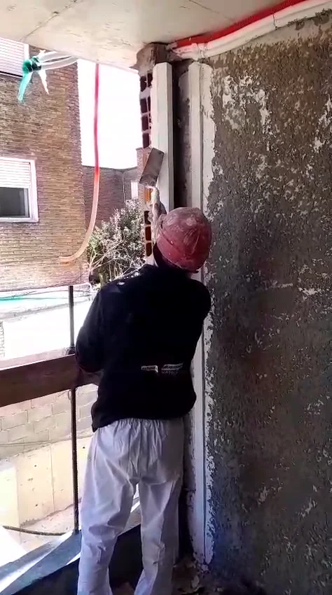 Operario terminando un revoque proyectado en una pared