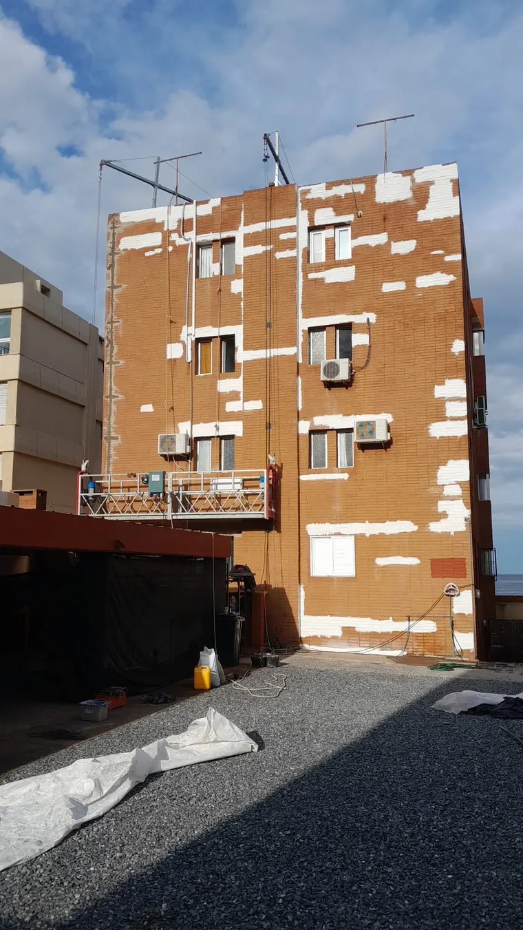 Fachada de edificio en obra, con reparaciones previas a la pintura